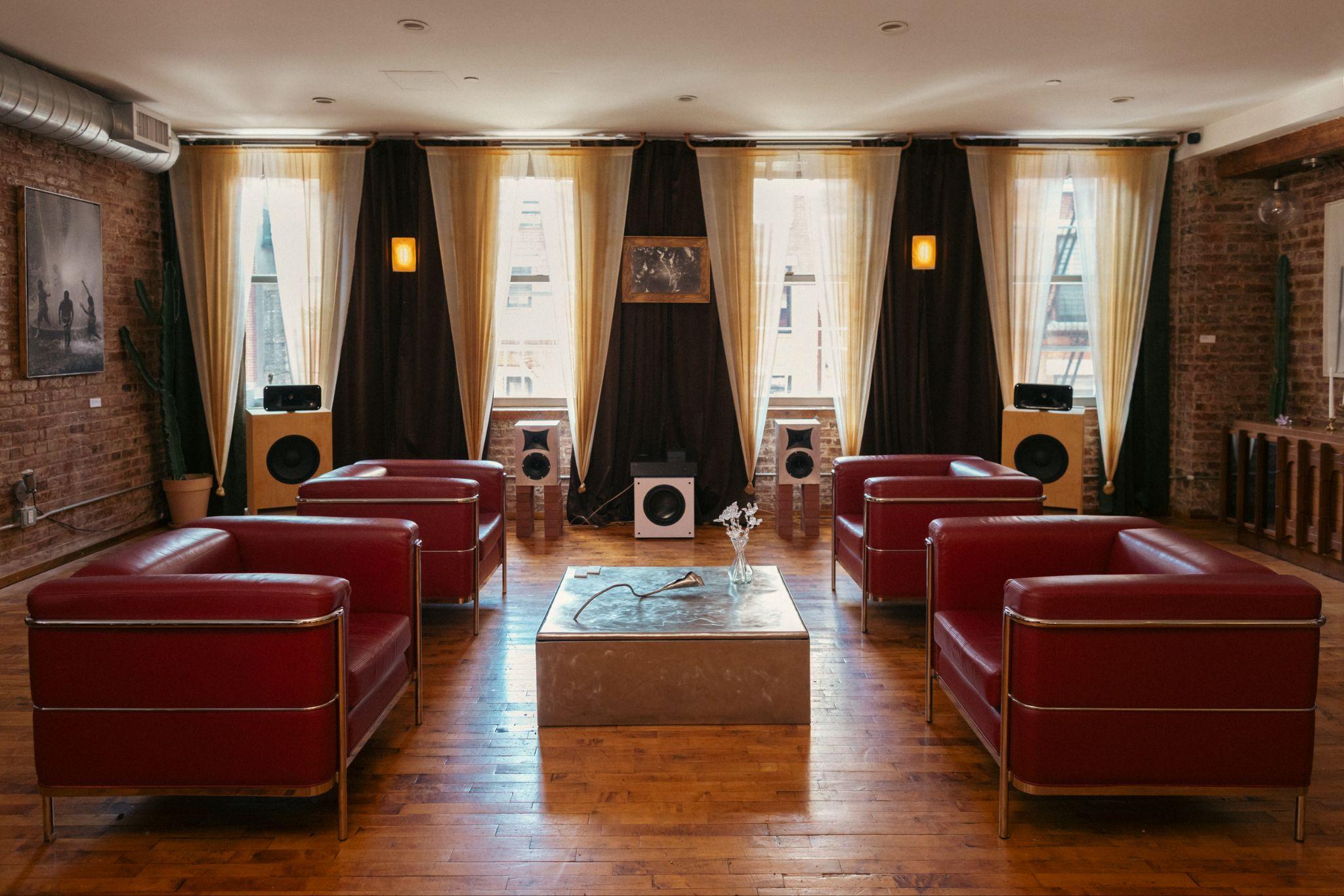 The Clearing at Fugue Gallery — red leather chairs around hand-built loudspeakers, sunlit loft windows and brick walls.